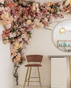 a chair and mirror in a room with flowers on the wall above it, along with a bar stool