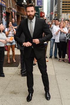 a man in a suit and tie is walking down the street with his hands on his hips