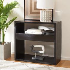 a black book shelf with a lamp on top of it next to a potted plant