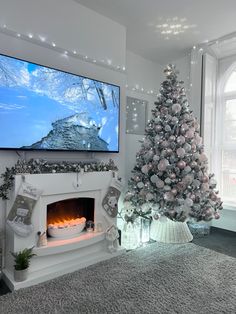 a living room with a christmas tree, fireplace and flat screen tv on the wall