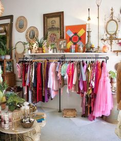 a room filled with lots of different types of clothing hanging on clothes racks and tables