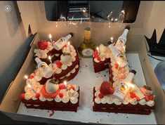 two slices of red velvet cake with white frosting and lit candles in a box