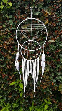 a white dream catcher sitting on top of a lush green field