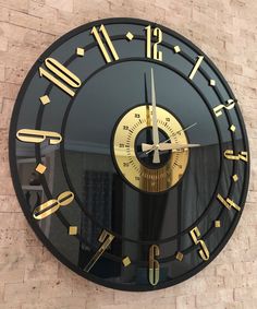 a black and gold clock on the side of a building with roman numerals