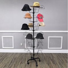 a hat rack with six hats on it in a room that has hardwood floors and gray walls