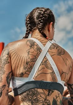 the back of a woman with tattoos on her upper and lower half, wearing a sports bra