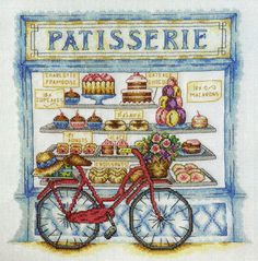 a cross stitch pattern with a bicycle and cakes on display in front of a store window