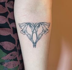 a woman's arm with a tattoo on it that has two flowers in the shape of a heart