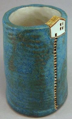 a blue vase with a small house on the inside and zippered in to it