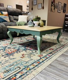 a living room with a couch, coffee table and rug on the floor in front of it