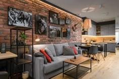 a living room filled with furniture next to a kitchen and dining room table in front of a brick wall