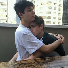 two young men hugging each other at a table