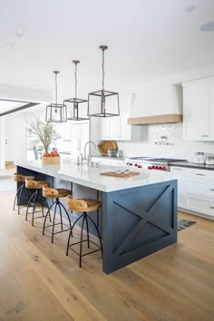 a large kitchen with an island and bar stools in the center, surrounded by white cabinets