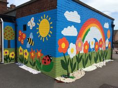 a painted mural on the side of a building in front of a brick wall with flowers and bees