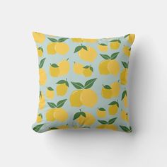 a yellow pillow with green leaves and lemons on it, against a light blue background