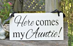 there is a sign that says here comes my auntie on it with flowers in the background