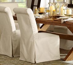 a dining room table with white chairs and candles