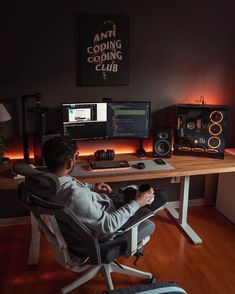 a man sitting at a desk in front of two computer monitors and a keyboard on it