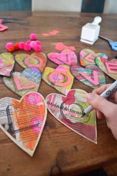 someone is making valentine's day cards out of old newspaper and paper hearts with the word love written on them