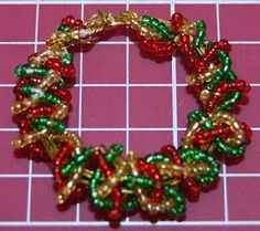 the beaded bracelet is made with red, green and gold beads on a pink background