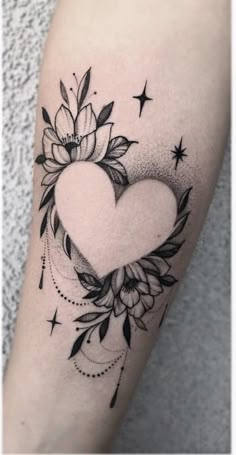 a black and white heart tattoo with flowers on the side of her arm, which is surrounded by stars