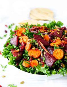 a salad with beets, carrots and pistachio seeds on a white plate