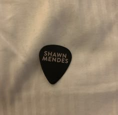 a black and white guitar pick with the words pawn mendes on it sitting on top of a white sheet