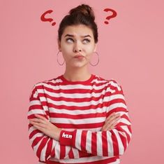 a woman with her arms crossed and looking at the camera while wearing a red and white striped shirt