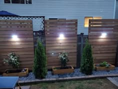 the lights are on in the garden by the house's privacy fence, which is lined with wooden planters