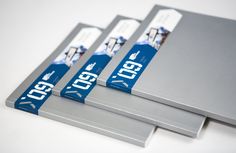 three metal folders with blue and white labels on them