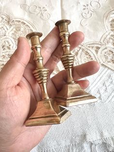 two brass candlesticks in the palm of someone's hand