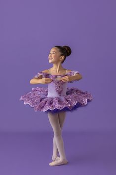 a young ballerina is posing for the camera