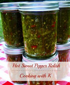 four jars filled with pickles sitting on top of a checkered tablecloth covered picnic table