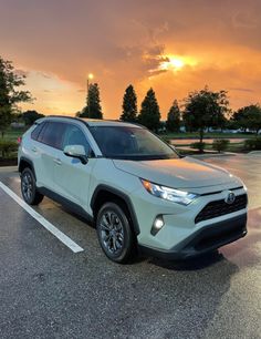 a white toyota rav parked in a parking lot with the sun setting behind it