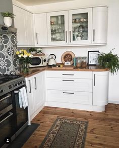 a kitchen with white cabinets and wood flooring is pictured in this image, there are flowers on the counter