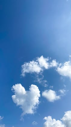 an airplane is flying high in the blue sky with white fluffy clouds and some green grass