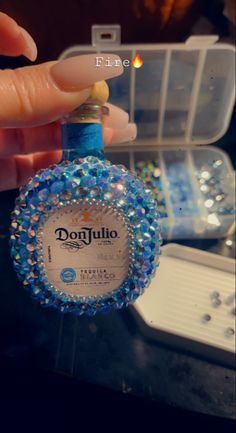 someone is holding a bottle with blue beads on it and there are other bottles in the background