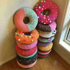 a stack of knitted donuts sitting on top of a wooden floor next to a window