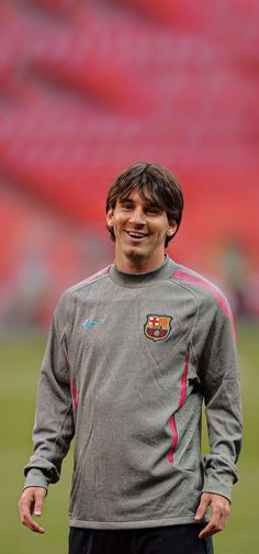 a man standing on top of a soccer field wearing a gray shirt and black shorts