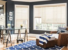 a living room with blue walls and white blinds on the window sill, two brown chairs