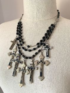 "Beautiful vintage silver cross spiritual statement necklace. This beautiful necklace features a collection of vintage silver & black crosses from France. The crosses hang from a cascade of vintage French black rosary chains. The rosary beads are made from wood. The large crosses are silver plated and are stamped Souvenir de Lourdes on the back. Overall necklace length is adjustable from 17-1/2\" to 21-1/2\", with a cross dangling from the end. The center  drapes down 4\". It fastens with a silv Luxury Crucifix Necklace As Gift, Handmade Black Crucifix Necklace, Black Crucifix Jewelry For Jewelry Making, Silver Crucifix Jewelry With Black Beads, Silver Rosary With Black Beads And Crucifix, Black Beaded Crucifix Jewelry, Vintage Black Cross Necklace, Handmade Black Cross Pendant Necklace, Handmade Black Cross Necklace