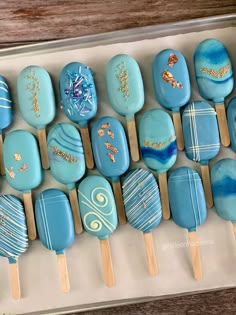 a box filled with lots of blue and white lollipops on wooden sticks