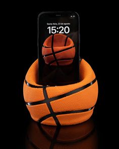 an orange and black basketball sitting on top of a cell phone holder in the shape of a basketball