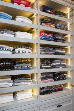 an organized closet with white drawers and lights