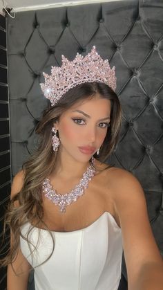 a woman in a white dress wearing a tiara and diamond necklace with matching earrings