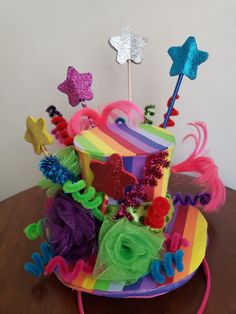 a multicolored birthday cake with stars and decorations on it sitting on a table