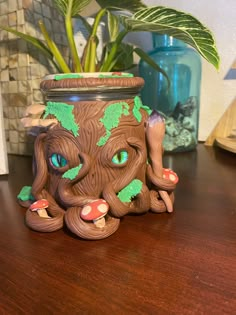 a potted plant with blue eyes sitting on a wooden table next to a vase