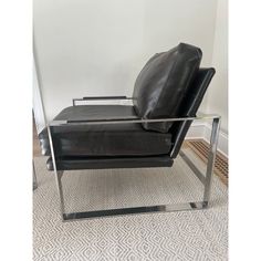 a black leather chair sitting on top of a carpeted floor next to a white wall