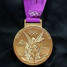 a gold medal with purple ribbon around it's neck and an olympic symbol on the front