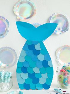 a blue paper fish sitting on top of a table next to plates and candy bars